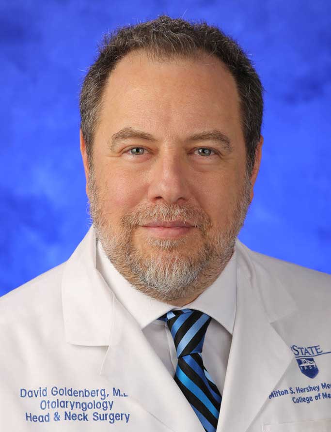 David Goldenberg, MD, FACS, is the Chair, Department of Otolaryngology - Head and Neck Surgery; Steven and Sharon Baron Professor at Penn State College of Medicine. He is pictured in a white medical coat against a blue background. 