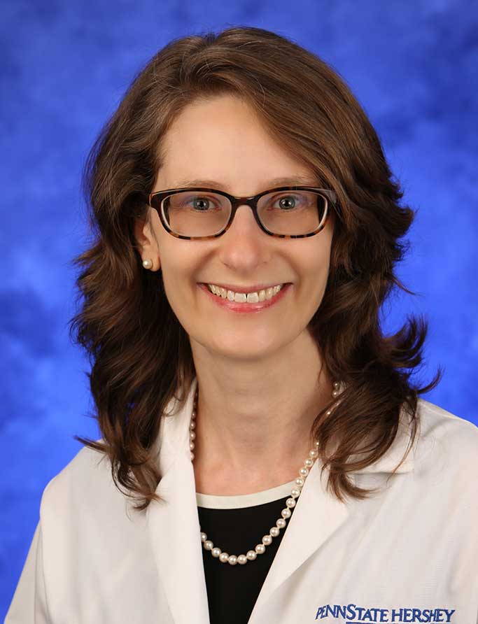 Erika Saunders, MD, is Chair of the Department of Psychiatry and Behavioral Health at Penn State College of Medicine. She is pictured in a dress shirt and medical coat against a blue background.