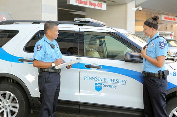 Two security guards talk in front of their car