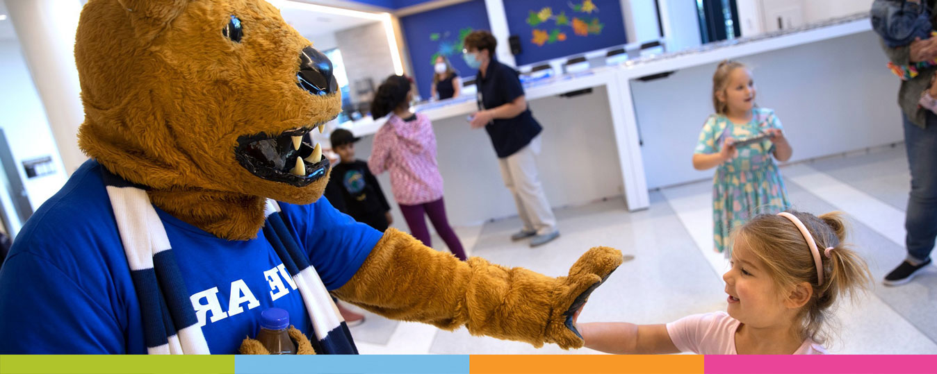 Young child giving the Penn State Nittany Lion a high five.