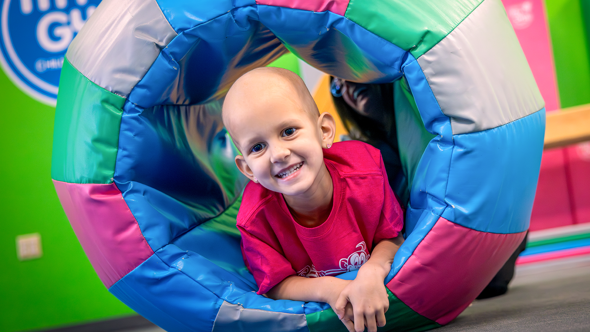 A young boy is smiling, while playing in an inflatable donut-type ball.