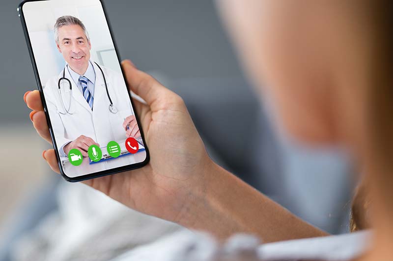 A closely cropped photo of a person videochatting with a doctor using a mobile phone.