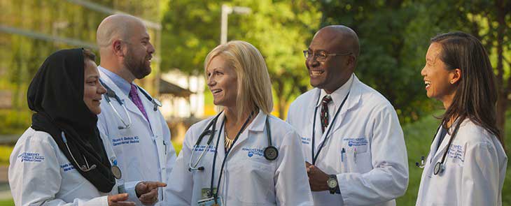 A group of Penn State Health physicians of different ethnicities enjoy a conversation on the Hershey campus.