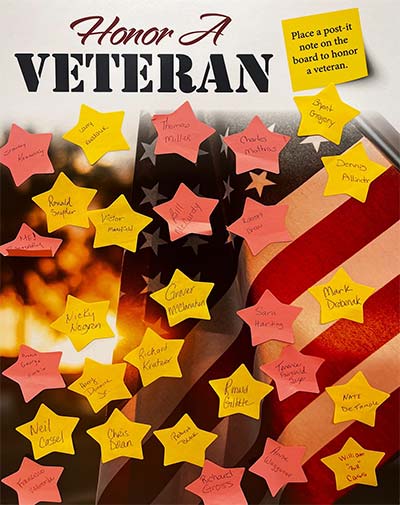 Honor a Veteran sign displays multiple star-shaped Post-it notes with the name of veterans.