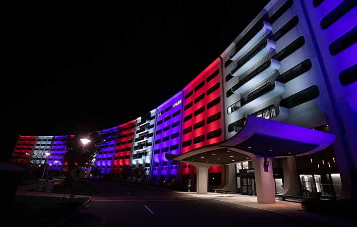 A night view of the Crescent of Penn State Health Milton S. Hershey Medical Center and Penn State College of Medicine is illuminated to represent the American flag colors of red, white and blue.