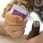 A teen steadies his hands on a table while he holds an e-cigarette in one hand and uses the other hand to refill the e-cigarette with liquid nicotine.