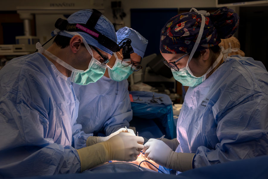 Three surgeons in the operating room performing a procedure on a patient.