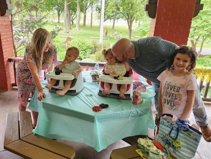 Young family celebrating twins birthday party outdoors.