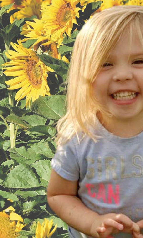 Young child smiling in a field of sunflowers