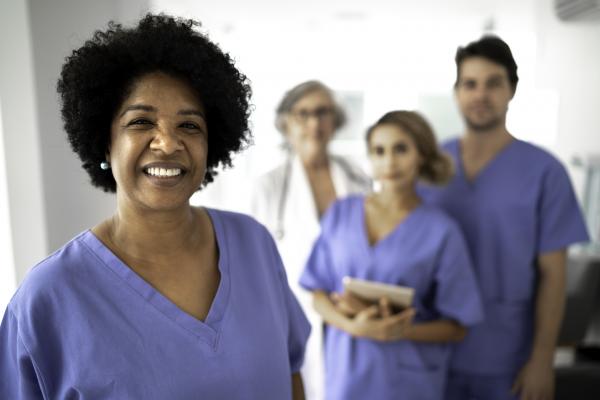 One nurse smiles at the camera while three other nurses stand behind them.