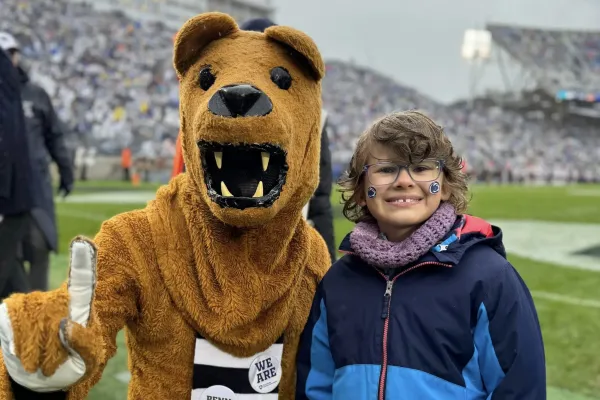 Young girl posing with the Penn State Nittany Lion on a football field