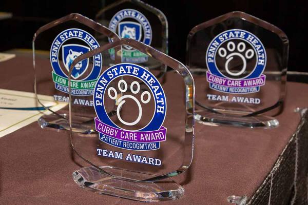 Penn State Health Cubby Care and Lion Care Awards are displayed on a table top