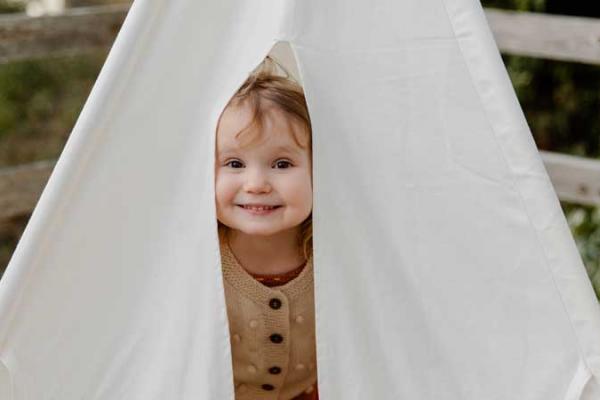 Happy little child smiling while peeking from tent.
