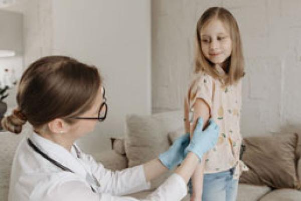 Image of girl with glucose monitor on her arm looking over her shoulder at physician 