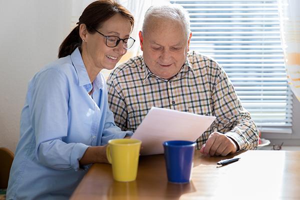 Caregiver and elderly man reading paperwork