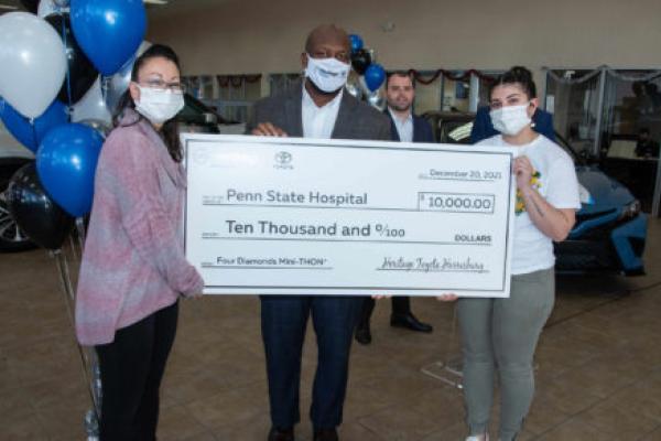 Three adults pose with an oversized check in the amount of $10,000 made payable to Four Diamonds Mini-THON at Penn State Health Children’s Hospital.