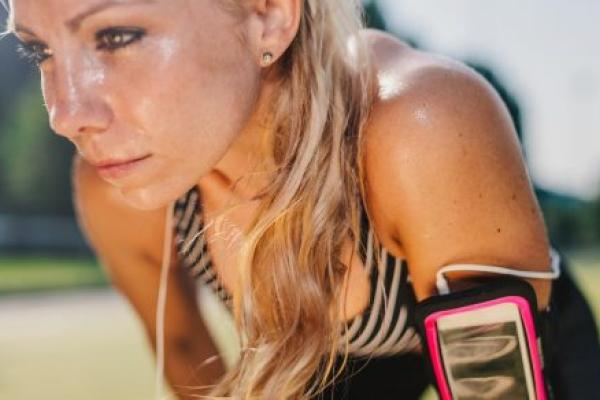 Sweaty, blond-haired woman resting after a hard workout on a sports field.
