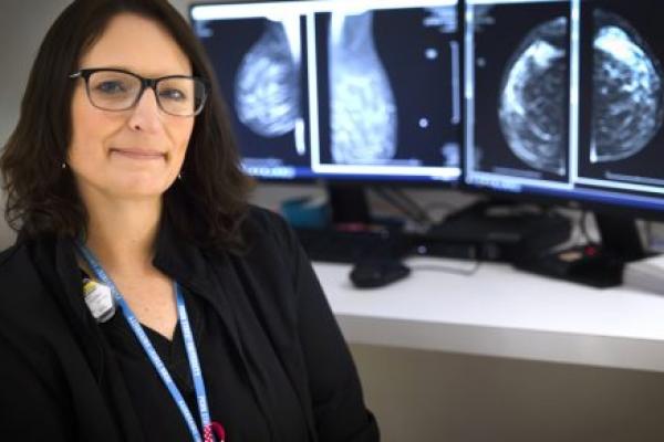 Radiologic technologist Erin Schaffner in her scrubs at Penn State Health Holy Spirit Medical Center. A mammogram scan is in the background on a computer screen.