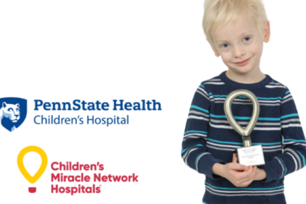 A young boy holds a small trophy. To his left are the logos for Penn State Health Children's Hospital and Children's Miracle Network Hospitals.