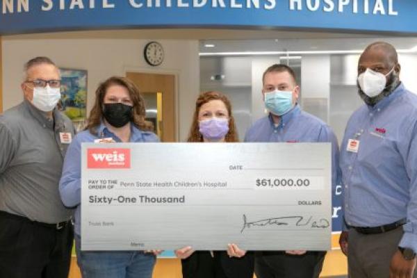 A group of people pose for a photo with a big check