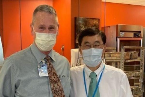 Gregg Atland, left, and Dr. Thomas Ma stand side by side wearing surgical masks