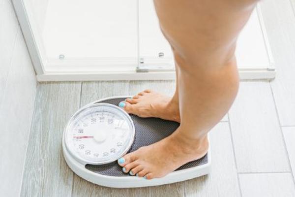 High angle view of a woman standing on a weight scale in a bathroom.
