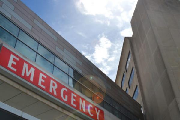 A view from below of a building bearing a red sign with the word “EMERGENCY” prominently displayed.