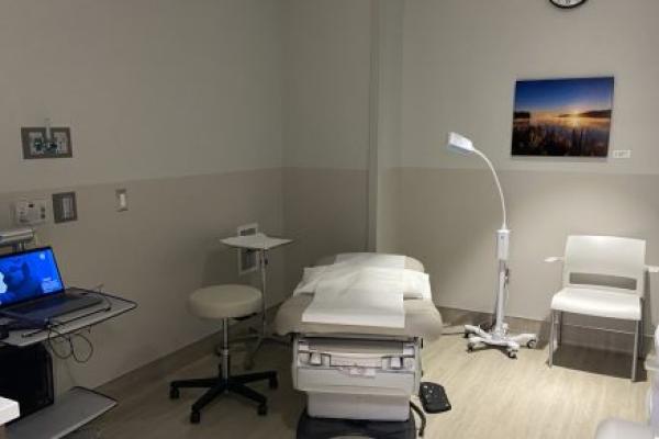 A clinic room with an exam chair, computer and various medical equipment.