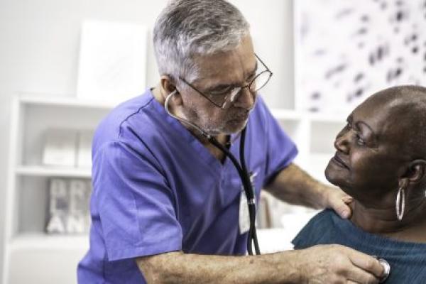 A doctor uses a stethoscope listen to the heartbeat of an older patient.