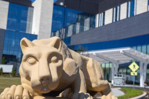 A photo of the Nittany Lion statue in front of a hospital