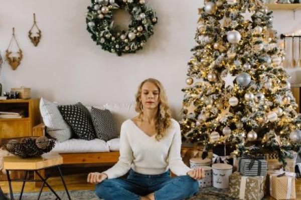 A woman meditates in a home decorated for the holidays.