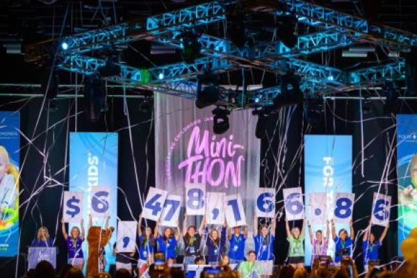 Student leaders on stage at the Four Diamonds Mini-THON Leadership Summit hold oversized number cards revealing the total amount raised for the 2025-26 school year.