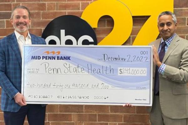 Two men are smiling and holding a big check for $214,000