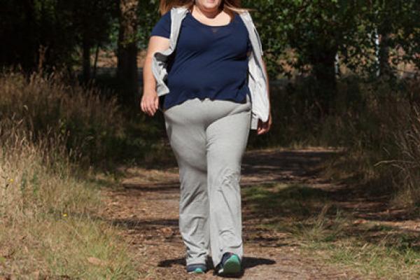 An overweight woman is pictured walking outdoors.