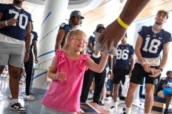 A young girl plays a bean bag game with members of the Penn State Football Team