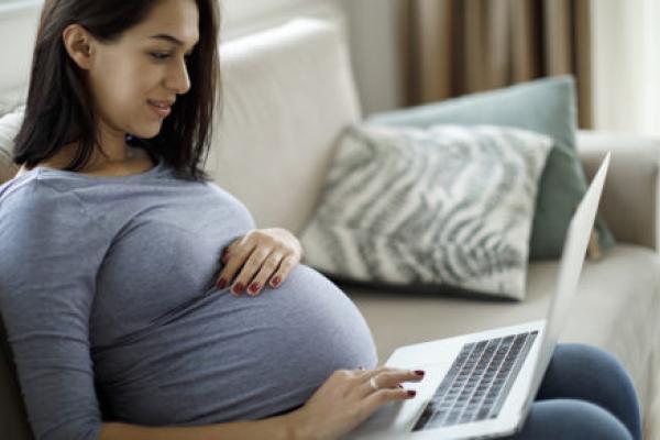 Pregnant woman using laptop at home