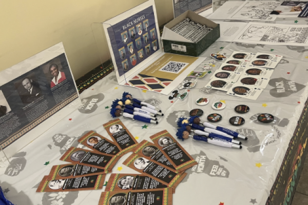 A display table containing Black History Month-themed items including flyers, slim jims, stickers and pens.