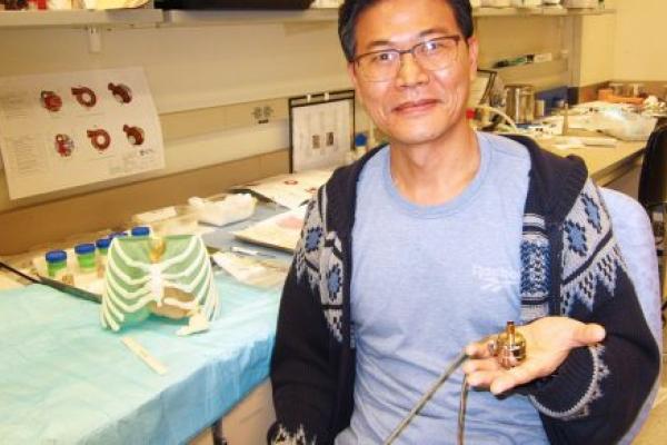 Scientist sitting in a lab and holding a prototype of a heart pump