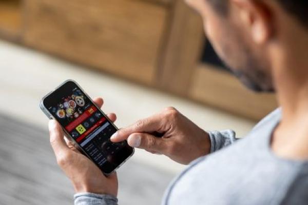 Man gambling online on a football game using his cell phone.