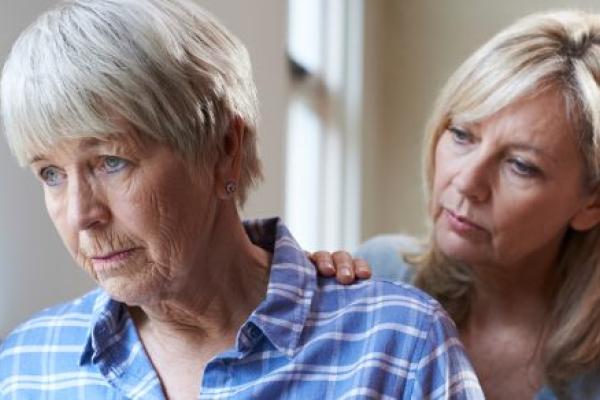 Adult daughter comforts her older mother, who appears sad.
