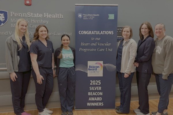Six people pose around a sign that says, "Congratulations to our Heart and Vascular Progressive Care Unit 2025 Silver Beacon Award Winners."