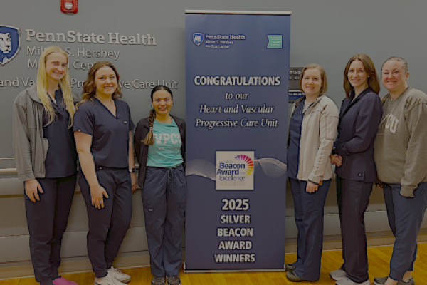 Six people pose around a sign that says, "Congratulations to our Heart and Vascular Progressive Care Unit 2025 Silver Beacon Award Winners."