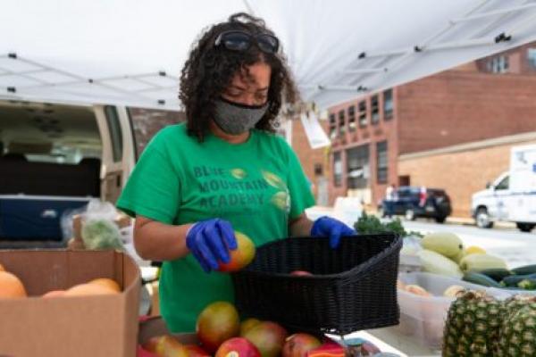 A woman arranges produce to be sold at a farm stand.