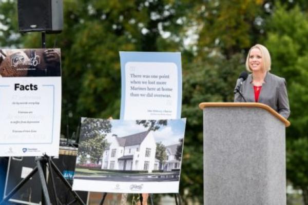 Dr. Jennifer Kraschnewski delivers a speech while standing at a podium at the groundbreaking ceremony for the first home being built as part of the Got Your 6 at Home initiative.
