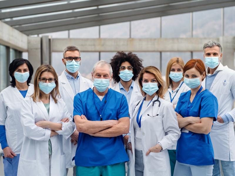 A group of healthcare professionals in masks look into the camera.