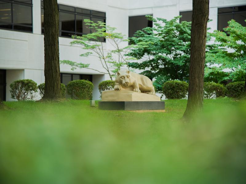 A nittany lion statue surrounded by greenery.