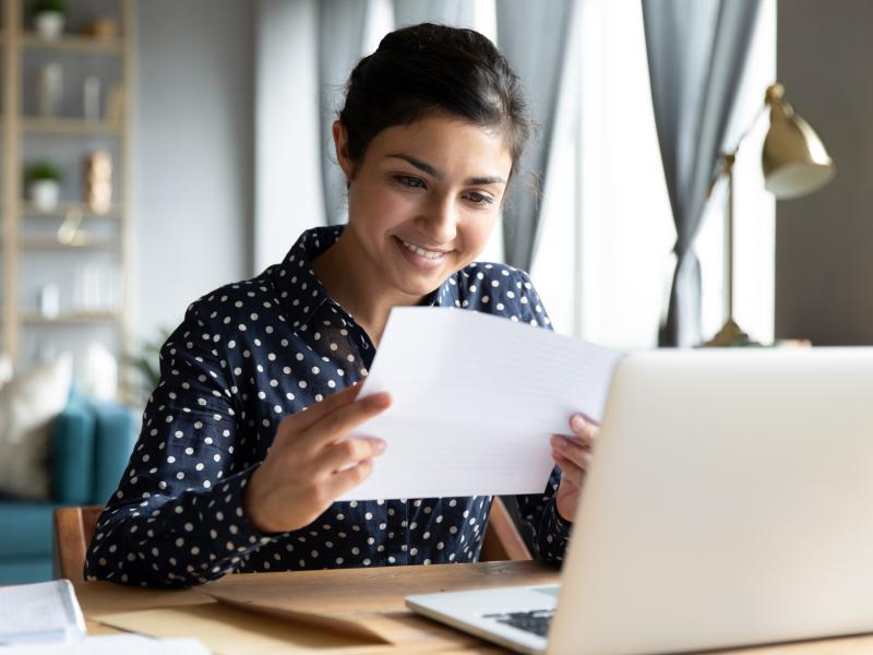 A woman looks at a piece of paper and smiles.