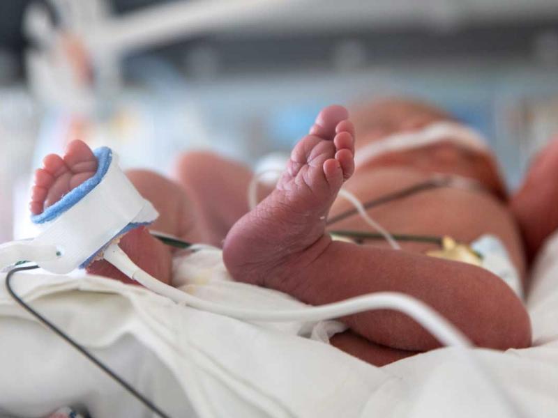 Newborn neonatal baby asleep in hospital infant warmer bed