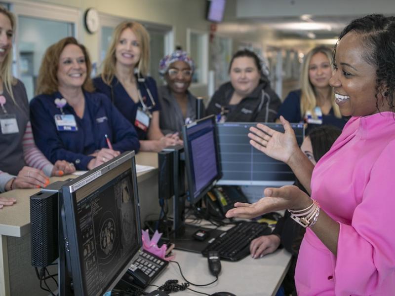 A nursing leader speaks to a team from behind a welcome desk.