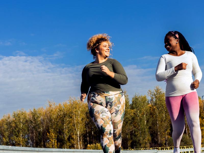 Two young plus size women jogging together.